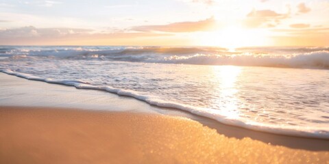 Obraz premium Golden hour on a serene beach with waves gently touching the shore, radiating a calming atmosphere.