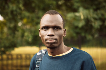 A young black man is walking in the park. Close up portrait.