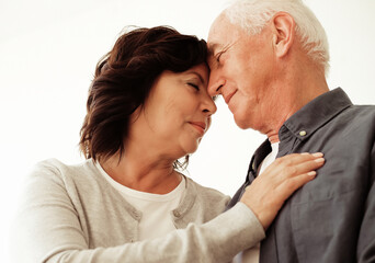 Portrait of cute happy Caucasian couple of retired husband and wife hugging indoors.