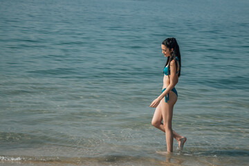 relaxed young woman walking along the beach shore