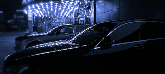 expensive Black cars standing in a row. Fleet of generic modern cars. Transportation. Luxury car fleet consisting. brandless. neon lights on background. luxury engine. night scene. executive class