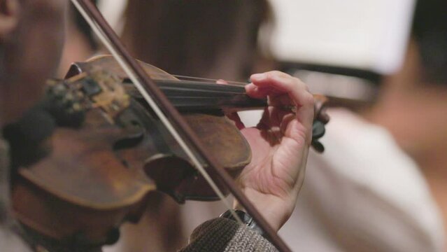 A slow motion video of a musician playing the violin or viola during a classical symphony orchestra rehearsal. Nr. 1