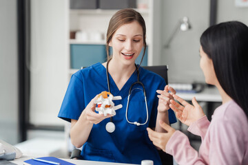 Caucasian female doctor explain to asian female patient using Human Anatomical Lumbar Disc...