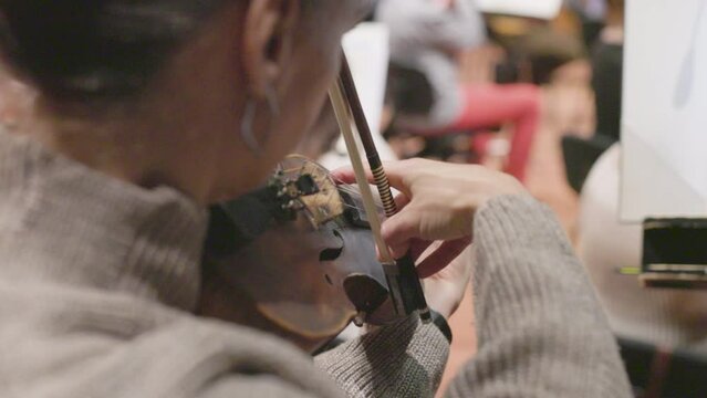 A slow motion shot of a musician on a violin or viola playing with the bow as well as using the pizzicato technique. Nr. 1