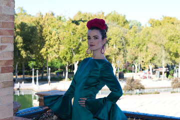Beautiful young woman with typical green frilly dress and dancing flamenco in plaza de espana in...
