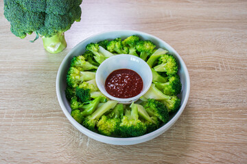 Blanched broccoli, vinegared red chili pepper paste and raw broccoli on wooden background.