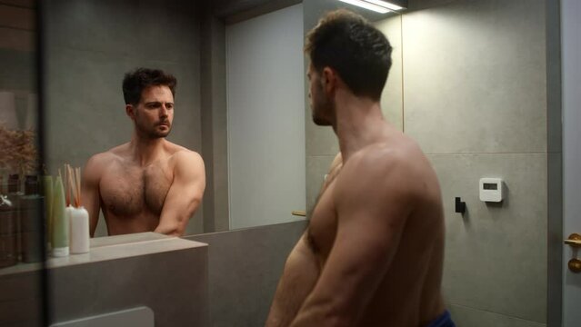 Caucasian man flexing muscles in the mirror