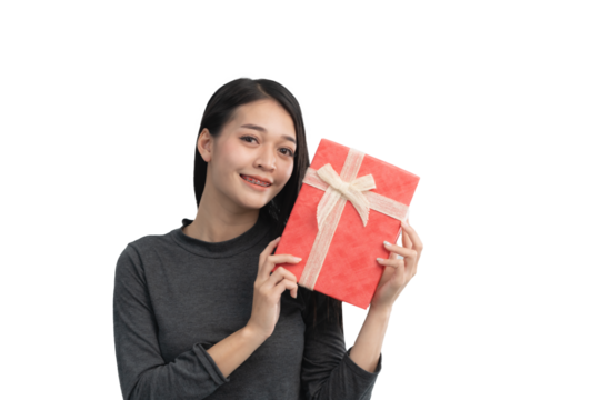 A woman is holding a red present with a bow on it. She is smiling and she is happy. Isolated on white background.
