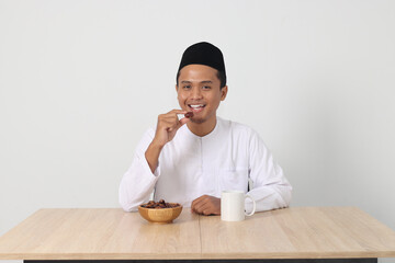Portrait of excited Asian muslim man eating kurma or date fruit during sahur and breaking fast....