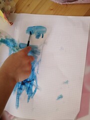 Child's hand and brush with paints. Blue