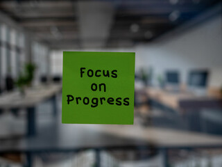 Post note on glass with 'Focus on Progress'.