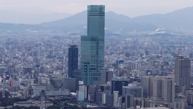 Aerial view of modern tall skyscraper towering above surrounding building in metropolis. Osaka, Japan
