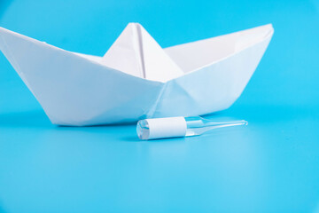 Vial, ampoule of the vaccine against the virus on a blue background with a paper boat and with a...