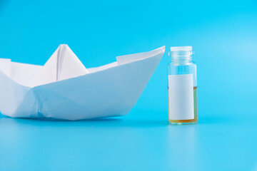 Vial, ampoule of the vaccine against the virus on a blue background with a paper boat and with a...