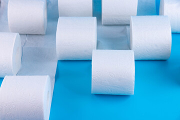 Rolls of white toilet paper on a blue background with place for text, advertising.