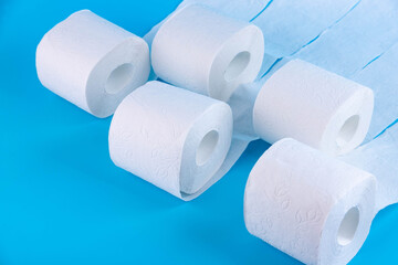 Rolls of white toilet paper on a blue background with place for text, advertising.