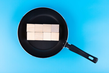 Concept for writing text on wooden blocks lying in a pan. Fictional news, fake news.