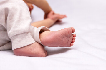 The little feet of a baby in panties lie on the bed. Selective focus.