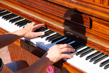 Hands are playing on an old piano in the park.