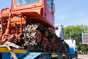 Old tractor bulldozer on a car platform.