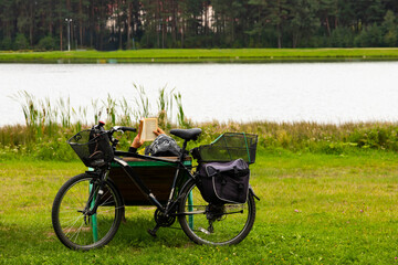A tourist on a bicycle stopped to rest on a sun lounger, read a book.