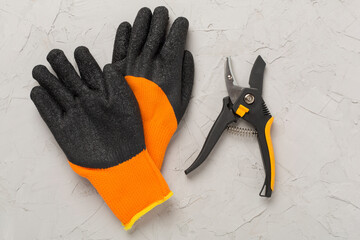 Secateurs and gloves on concrete background, top, view
