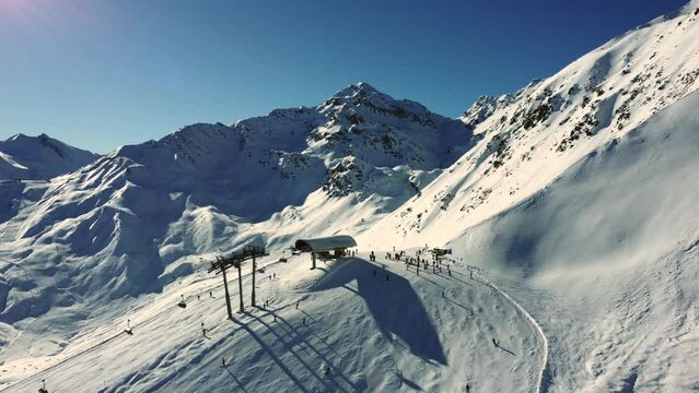 Chairlift end station with skiers high in Alps during winter season, aerial