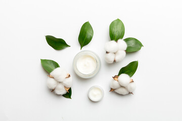 Organic cosmetic products with cotton flower and green leaves on white background. Flat lay