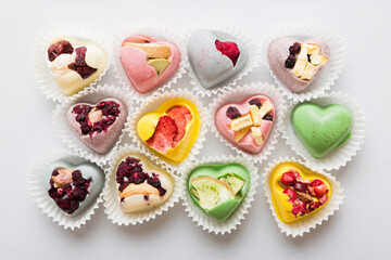 chocolate sweets in the form of a heart with fruits and nuts on a colored background. top view with space for text, holiday concept