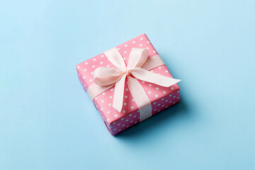 wrapped Christmas or other holiday handmade gift box in color paper with ribbon on colored...