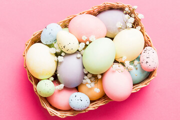 Happy Easter composition. Easter eggs in basket on colored table with gypsophila. Natural dyed colorful eggs background top view with copy space