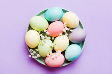 Happy Easter composition. Easter eggs in basket on colored table with gypsophila. Natural dyed...
