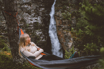 Woman enjoying waterfall view lying in hammock in forest travel lifestyle outdoor with camping gear summer vacations girl hiking in Norway eco tourism adventure trip in the wild - 763059047