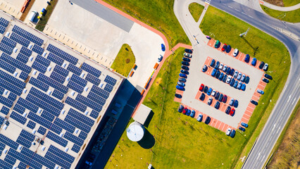 Electric cars charging from a solar power plant on the roof of a warehouse. Sustainable technologies reduce emissions in transport. - 763059812