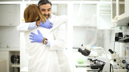 Joyful laboratory colleagues sharing a success moment with an embrace