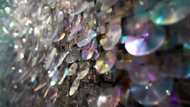 An upclose look at a large wall installation made from layers of discarded CDROMs and floppy disks creating a sparkling and textured surface.