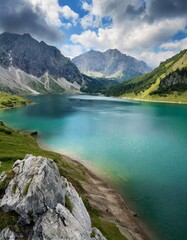 Naklejka na ściany i meble A calm blue mountain lake reflects the snow-capped peaks and fluffy white clouds of a scenic summer landscape