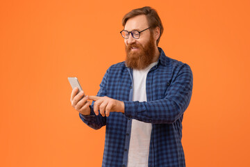 guy with red hair and beard browses on smartphone, studio
