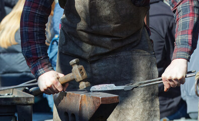 Midsection body of blacksmith demonstrates an anvil forging demonstration at the Easter Farmers...