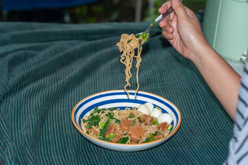 a woman's hand is scooping instant noodles