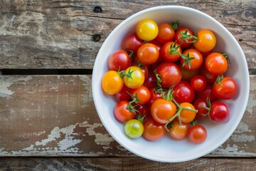 Overhead shot of organic, heirloom baby tomatoes in a white bowl on a rustic wood table. - Powered by Adobe