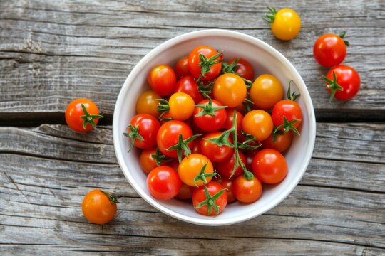 Overhead shot of organic, heirloom baby tomatoes in a white bowl on a rustic wood table.