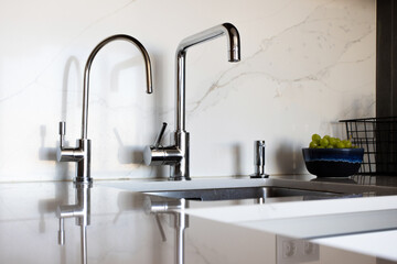Kitchen brass utensils, chef accessories. Hanging modern kitchen with white marble wall and stone tabletop.
