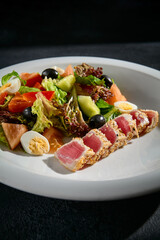 Close-up of Niçoise salad with medium seared tuna on a white plate