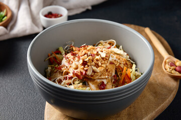 Salad with glass noodles, vegetables, and tofu with a nut dressing on a wooden stand