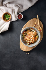 Glass noodle salad with vegetables and tofu in nut dressing, top view on a wooden cutting board