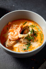 Tom Yum seafood soup with shrimp and mussels, front view on a dark slate