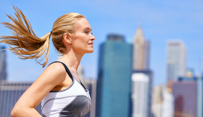 Woman, outside and running for fitness in city, jogging active and fit female person exercise in...