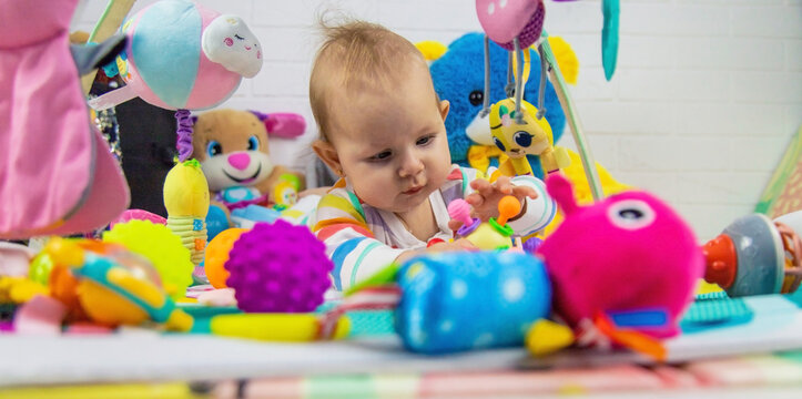 a child plays with hanging toys on a play mat. the child plays with toys at home.