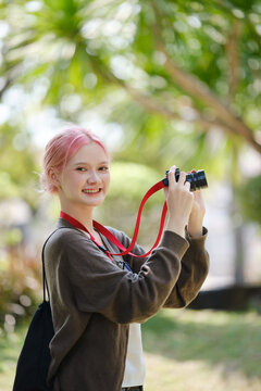 Beautiful Young artist Woman taking photo in flowers garden. Young cute girl carry the camera in the garden.